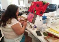 A woman painting florals on canvas.