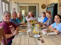 Ladies sitting at a farmhouse style table enjoying breakfast on the screened porch.