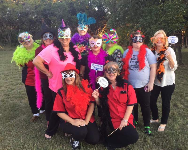 Ten ladies in colorful costumes and masks.