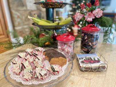 A tray of chocolate-dipped cookies, peppermint bark and canisters of peppermints.