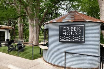 Trees overhanging a rustic metal building with a 