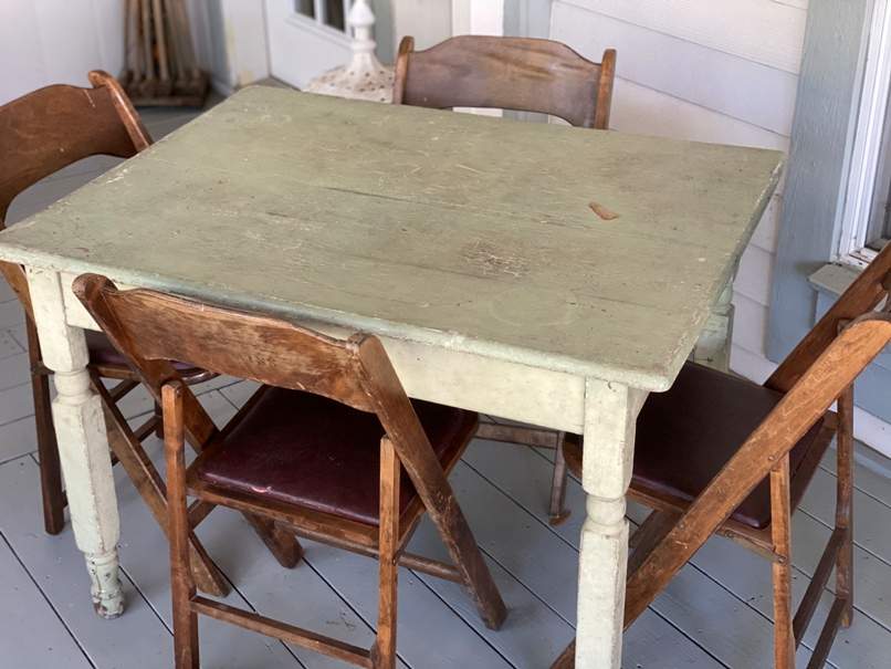 Green vintage farmhouse table and four folding chairs.