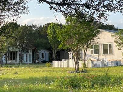 Scenic view of wildflowers in foreground and in the distance a little  white chapel and across from it a white picket fence area.