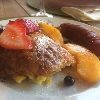 Peach croissant French toast A baked croissant drenched in butter-warmed strawberries, peaches, and blueberries and dusted with powdered sugar.