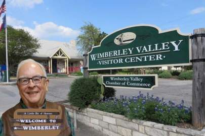 Volunteer John Kimbrew in front of the Wimberley Valley Visitor Center and sign.