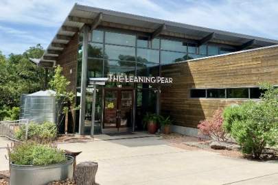 Entrance to The Leaning Pear a modern style building with sloped roof and glass walls. A steel water collection system is attached to the left side of the building.