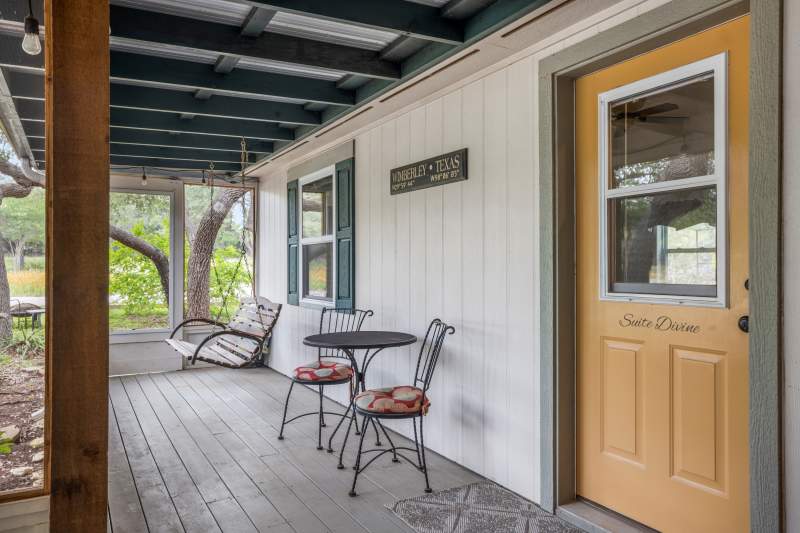 Background is a porch swing. Foreground is a bistro table set for two and the private entrance to Suite Divine on the inn's front porch.