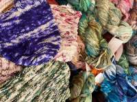 An assortment of colorful woven textiles and skeins of hand-dyed yarn.