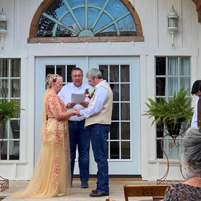 Wedding ceremony in front of small, white chapel.