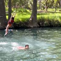 Swimmer drops from a rope swing into Blue Hole's crystal clear water. 