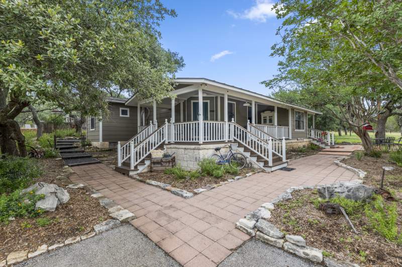 Charming house and elevated covered front porch with three sets of stairs.