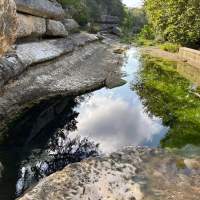 Beautiful, natural spring surrounded by large rocks and vegetation.