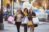 Three women walking down the street holding several colorful shopping bags.