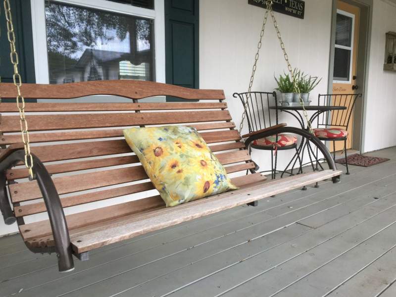 Background is a porch swing. Foreground is a bistro table set for two and the private entrance to Suite Divine on the inn's front porch.