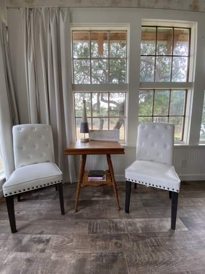 Small table with two white, padded side chairs for inside dining, reading, table games.