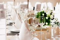 Elegant table setting with white folded napkins, white floral arrangements and crystal wine glasses.